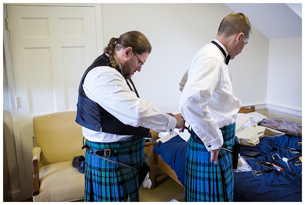 groom and groomsmen getting dressed in kilts