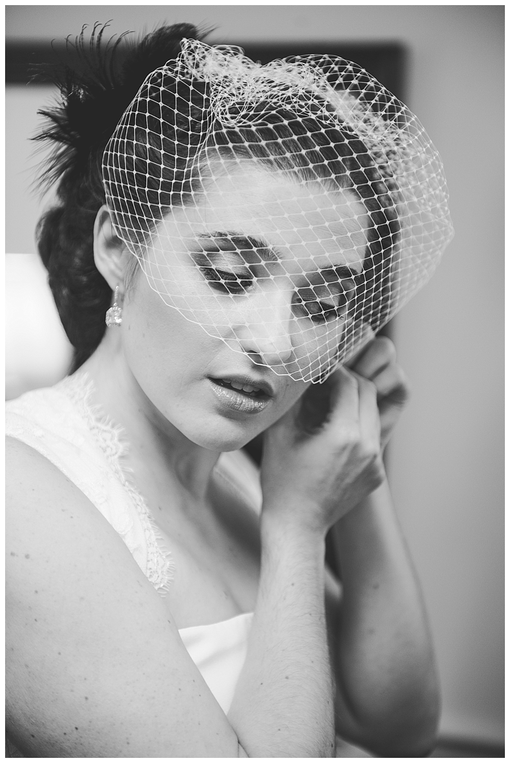 black and white portrait of bride putting on earrings