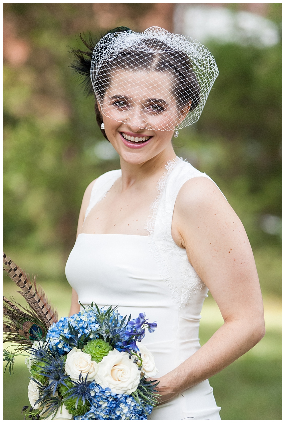 Bridal portrait with birdcage veil and blue bouquet with feathers