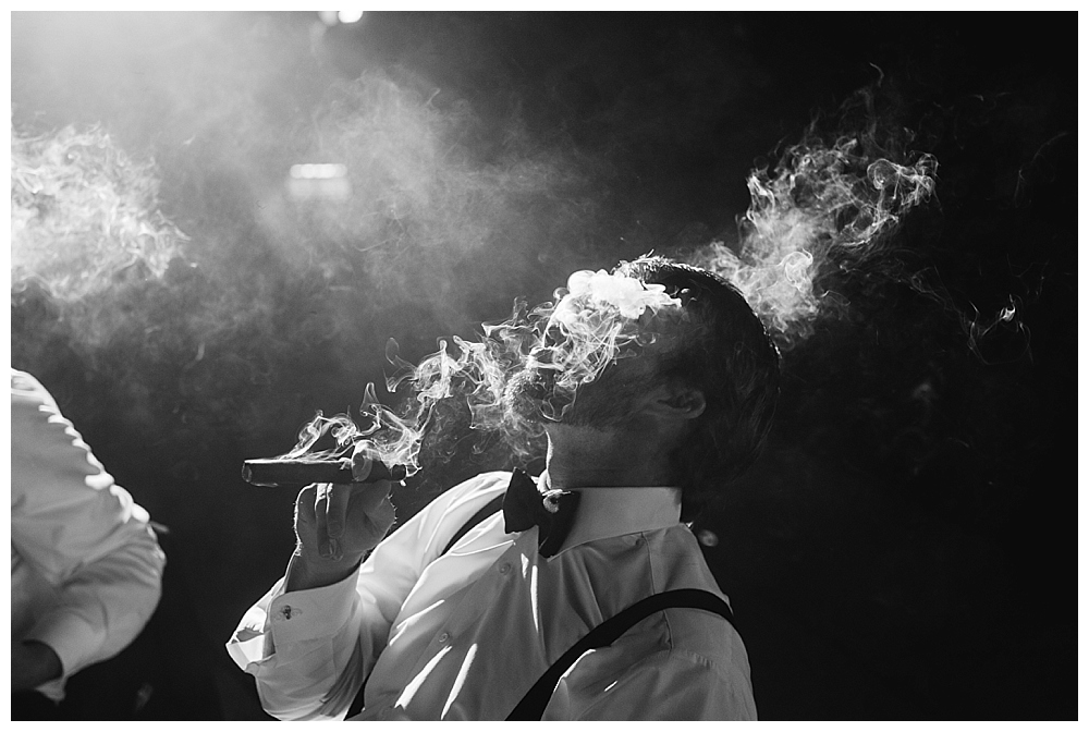 groom smoking cigars wedding