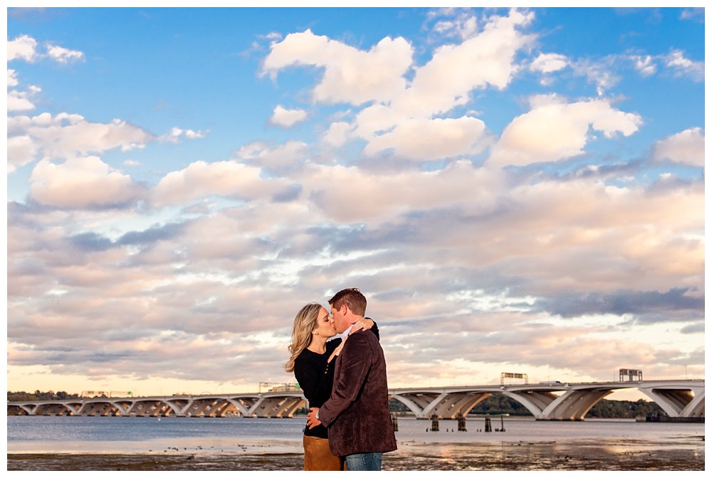 Engagement session in Old Town Alexandria on the water with gorgeous clouds and bridge in background